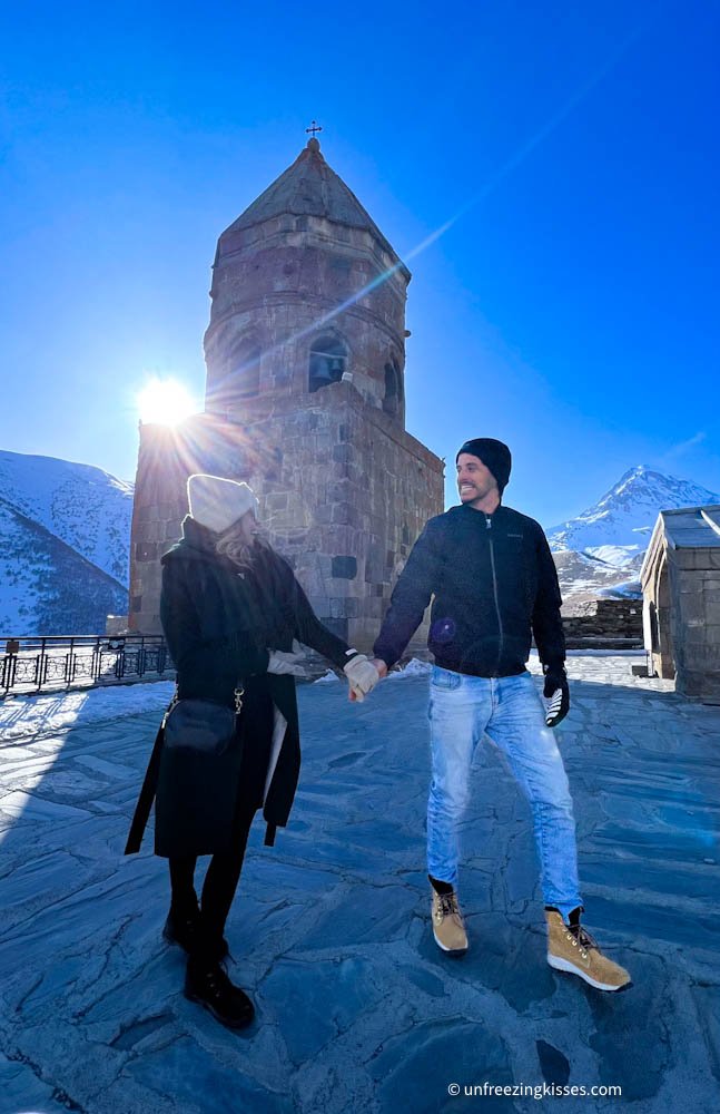 A couple and Gergeti Trinity Church Kazbegi Georgia